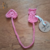 Un marque-pages plat en forme de chat rose, crocheté avec du fil coton.